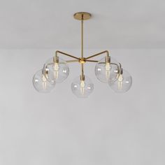 three clear globes hanging from a brass chandelier with four bulbs on each end