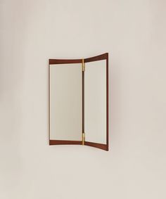 a mirror mounted to the side of a white wall next to a wooden framed object