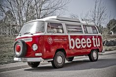 an old red and white van driving down the street