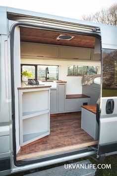 the interior of a camper van with its door open and kitchen area in place