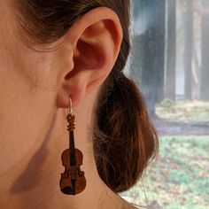 a close up of a person wearing earrings with a violin on it's ear