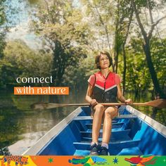 a woman is sitting in a boat on the water with trees and foliage behind her