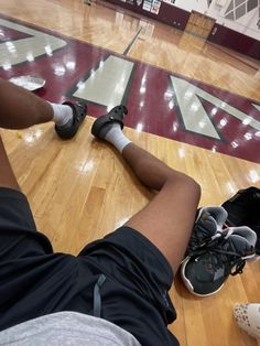 two people sitting on the basketball court with their feet propped up and wearing sports shoes