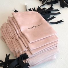 a stack of pink napkins sitting on top of a white table next to black leaves