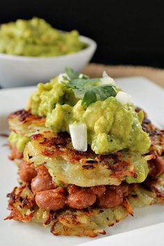 a stack of food on a plate with guacamole in the middle and another bowl behind it