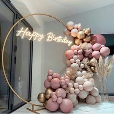 a happy birthday balloon arch with pink and gold balloons on it in front of a window