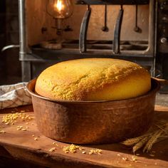 a loaf of bread sitting in a metal pan on a wooden table next to an oven