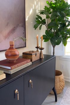 a table with books, candles and a potted plant sitting on top of it