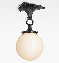 a light fixture hanging from the ceiling on a white wall behind it is an object in the shape of a flower