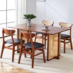 a dining table with four chairs and a plant in the corner on top of it