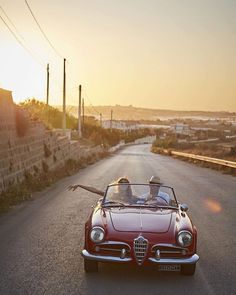 a red convertible car driving down a street