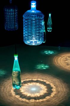 three water bottles sitting next to each other on top of a table in the dark