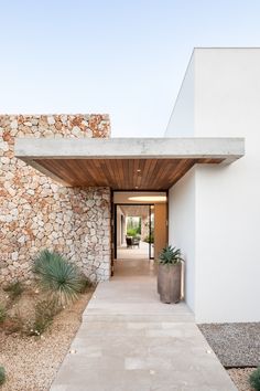 an entry way to a house with stone walls and plants on the side walk leading up to it