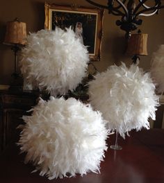 three white feathers sitting on top of a wooden table next to a lamp and pictures