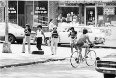 black and white photograph of people on bicycles in the street