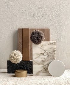 marble, wood and other decorative items are arranged on a white rug in front of a wall