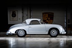 an old white sports car parked in a garage