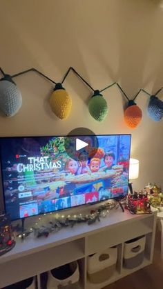 a flat screen tv sitting on top of a white table next to christmas decorations and lights