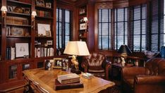 a living room filled with furniture and bookshelves next to a window covered in shutters