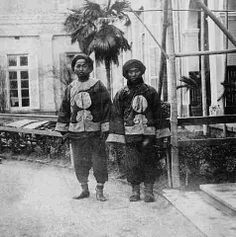 two men standing next to each other in front of a building