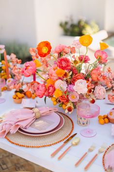 the table is set with pink and orange flowers in vases, plates, napkins, and utensils