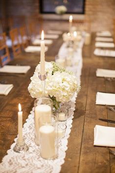 a long table with white flowers and candles