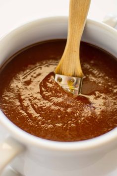 a wooden spoon in a white cup filled with hot chocolate