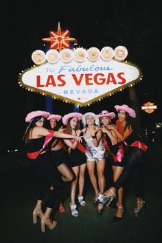 a group of women posing in front of the las vegas sign