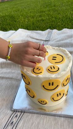 a woman is cutting into a cake with smiley faces on it