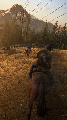 two men riding horses on a dirt road in front of a mountain with power lines