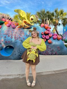 a woman is standing in front of a fake sea life wall holding a stuffed animal