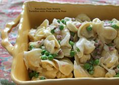 a yellow bowl filled with pasta and peas on top of a table next to a colorful cloth