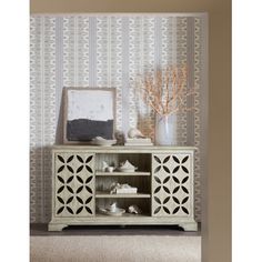 a white cabinet sitting in front of a wall with a vase on top of it