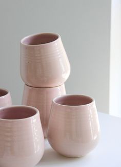 four pink vases sitting on top of a white table next to eachother