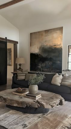 a living room filled with furniture and a large painting on the wall above it's coffee table