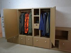 an open closet with clothes hanging on the doors and drawers in front of it, next to a tiled floor