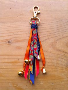 a keychain made out of fabric with bells attached to it on a wooden surface