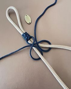 a white and blue rope tied to a metal hook on a gray surface with a button