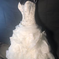 a white wedding dress is displayed on a mannequin in front of a black background