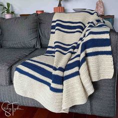 a blue and white crocheted blanket sitting on top of a couch next to a potted plant