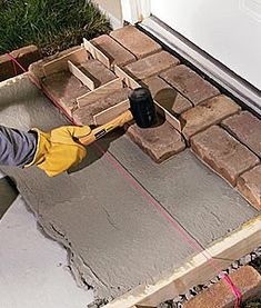 a man using a power drill to build a brick wall in front of a house