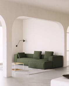 a green couch sitting in the middle of a living room next to a white wall