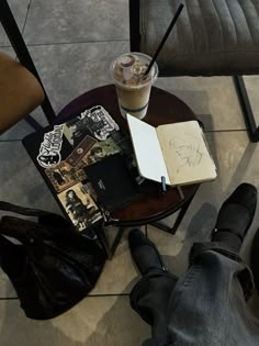 a person sitting at a table with a book, notebook and coffee cup on it