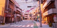 an empty city street with buildings on both sides and power lines above the road that runs through it