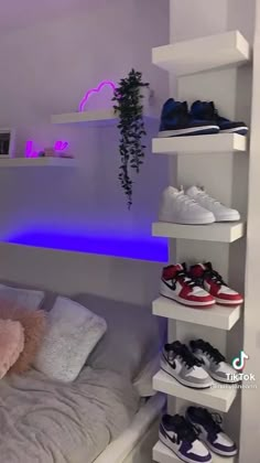 there is a bed that has some shoes on top of it and shelves with plants in the corner