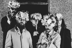 four men with flowers in their hair standing next to each other