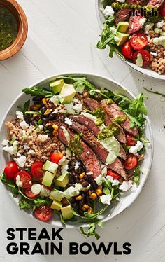 two plates filled with steak and salad on top of a white table