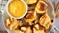 hot dogs and buns are on a plate with dipping sauce next to them,