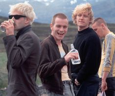 three young men standing next to each other with one holding a bottle in his hand