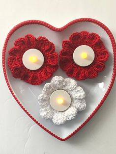 two crocheted heart shaped candles on a plate with a candle holder in the shape of a heart